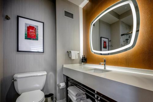 a bathroom with a toilet and a sink and a mirror at Hotel Indigo Baton Rouge Downtown by IHG in Baton Rouge
