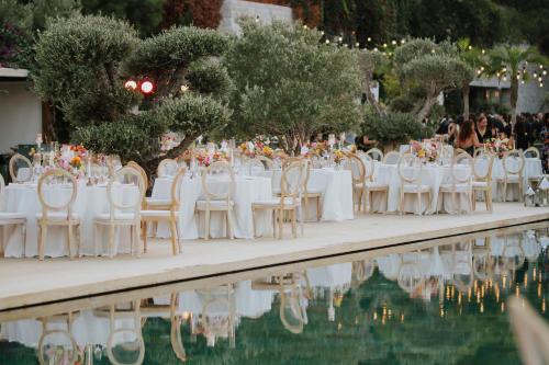 a wedding reception with white tables and chairs next to a pool at The Bodrum EDITION in Yalıkavak