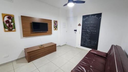 a living room with a couch and a chalkboard on the wall at Ap Ubatuba in Ubatuba