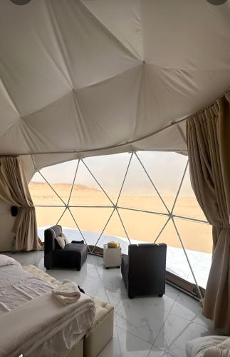 a room with a tent with a bed and two chairs at Rum Honeymoon Camp in Wadi Rum