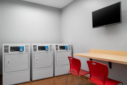 a room with four washing machines and a table with red chairs at TownePlace Suites by Marriott Champaign in Champaign