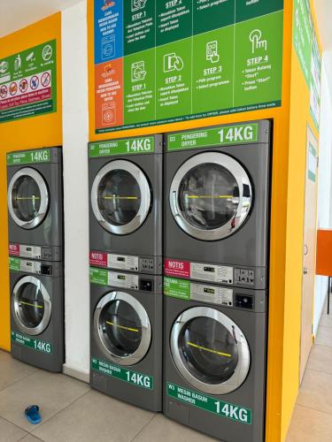 four washing machines are lined up against a wall at 2BR Apartment - Beachfront - Corner Unit - Netflix - Unifi 300mbps - Mutiara Melaka Pantai Puteri in Malacca