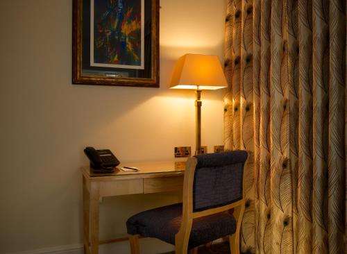 a desk with a chair and a lamp and a phone at GreyFriars in Colchester