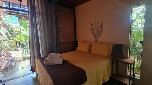 a bedroom with a bed and a large window at Casa jardim com ofurô - Chapada dos veadeiros in Cavalcante