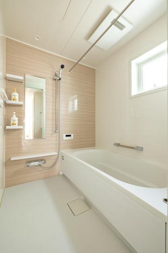 a white bathroom with a tub and a window at 鎌倉-Reihome in Kamakura