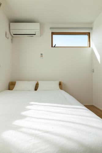 a white bed in a room with a window at 鎌倉-Reihome in Kamakura