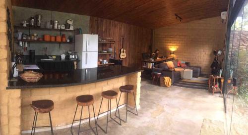 a kitchen with a bar with stools in a room at Casa jardim com ofurô - Chapada dos veadeiros in Cavalcante