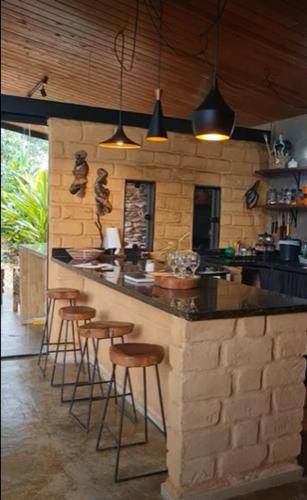 a kitchen with a counter and bar stools in it at Casa jardim com ofurô - Chapada dos veadeiros in Cavalcante