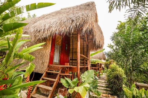 a small hut with a thatched roof in a garden at Sten Lodge in Labuan Bajo