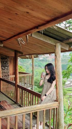 a woman sitting on a porch with a cup of coffee at Toce House Tả van in Sa Pa
