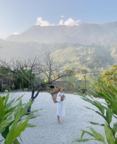 a woman in a white dress standing on a gravel field at Toce House Tả van in Sa Pa