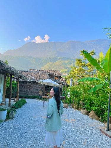 a woman holding an umbrella in front of a house at Toce House Tả van in Sa Pa