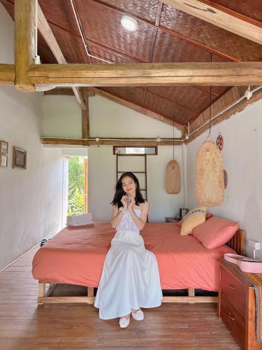 a woman in a white dress sitting in front of a bed at Toce House Tả van in Sa Pa
