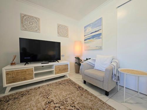 a living room with a television and a chair at Noosa River Retreat Holiday Apartments in Noosaville