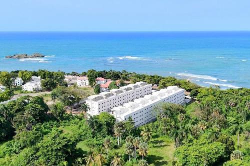 an aerial view of a white building on a hill next to the ocean at Brand New Beachfront Sunset Apartments in San Felipe de Puerto Plata