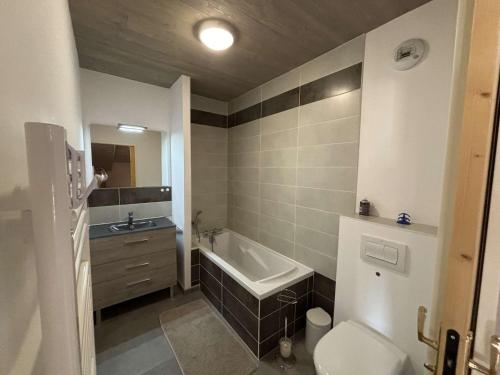 une salle de bain avec une baignoire, des toilettes et un lavabo dans l'établissement Appartement moderne 5 pièces, proche des pistes avec cheminée, terrasse, parking et bois inclus - FR-1-297-346, à Auris