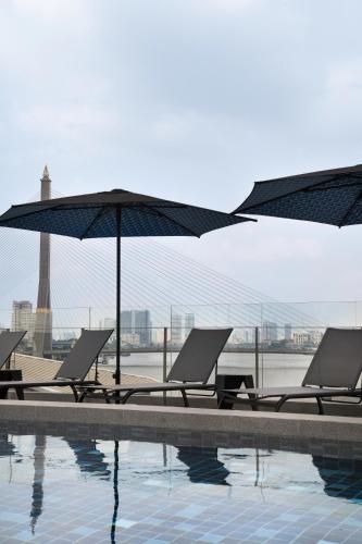 a group of chairs and umbrellas next to a swimming pool at The StandardX, Bangkok Phra Arthit in Bangkok