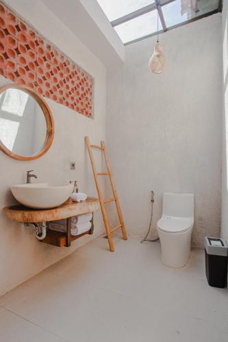 a bathroom with a sink and a mirror and a toilet at Thousand Sunday Ubud in Ubud
