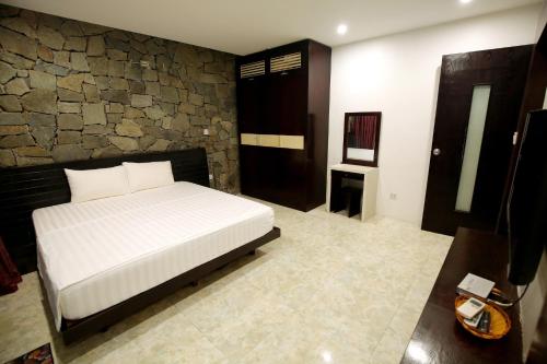 a bedroom with a bed and a stone wall at Biệt Thự chủ nhà tự doanh tại FLAMINGOS ĐẠI LẢI RESORT in Phúc Yên