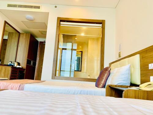a hotel room with two beds and a mirror at Lenid Ocean View Hotel in Nha Trang