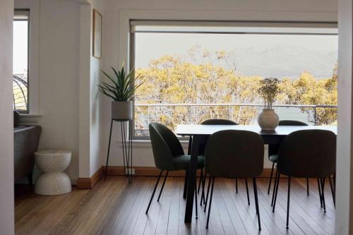 a dining room with a table and chairs and a large window at Waterfront home with outdoor spa bath and mountain views - 5 min drive to city in Montagu Bay