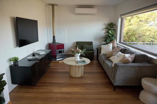 a living room with a couch and a table at Waterfront home with outdoor spa bath and mountain views - 5 min drive to city in Montagu Bay