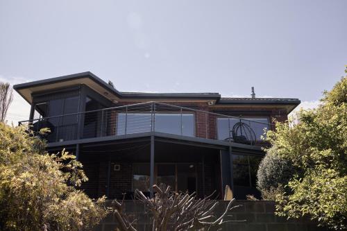 a house with a balcony on the side of it at Waterfront home with outdoor spa bath and mountain views - 5 min drive to city in Montagu Bay