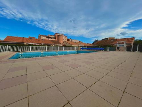 une piscine vide avec des bâtiments en arrière-plan dans l'établissement Pavillon climatisé proche plage avec piscine à Argelès-sur-Mer - FR-1-388-227, à Argelès-sur-Mer