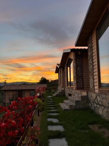 a pathway next to a house with red flowers at Guest House Si n'shpi tande - Mrizi i Zanave in Fishtë