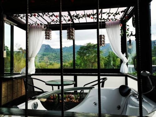 a room with a tub and a large window at Keeree Loft Resort คีรีลอฟท์รีสอร์ท in Thong Pha Phum