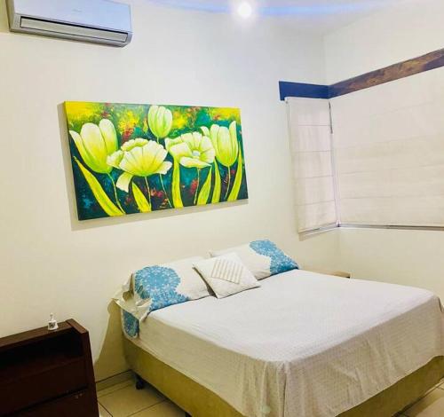 Un dormitorio con una cama con un cuadro en la pared. en Los Mangales, en Villamontes