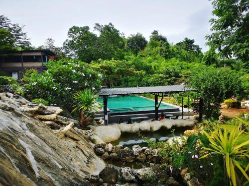 a swimming pool in a garden with a waterfall at Keeree Loft Resort คีรีลอฟท์รีสอร์ท in Thong Pha Phum