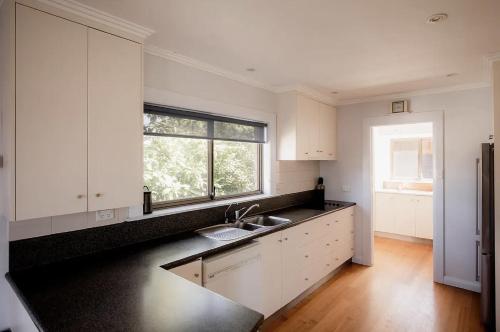 a kitchen with white cabinets and a sink and a window at Waterfront home with outdoor spa bath and mountain views - 5 min drive to city in Montagu Bay