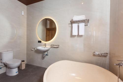a bathroom with a toilet and a sink and a mirror at Sujiwa Ubud Hotel & Villa in Ubud