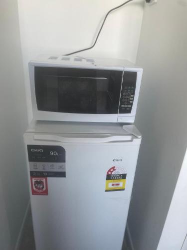 a microwave sitting on top of a refrigerator at Spacious studio unit in Rochedale South