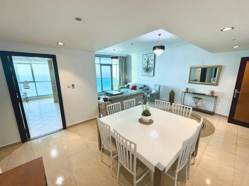 a dining room with a white table and chairs at Luxury Corniche Residence 2 BHK pool gym wifi sea front in Ajman