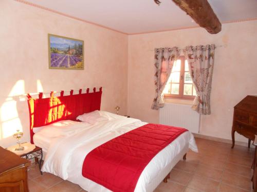ein Schlafzimmer mit einem großen Bett mit einer roten Decke in der Unterkunft Les Jardins de Bouteille in Manosque