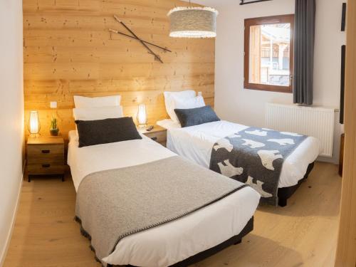 - une chambre avec 2 lits et une horloge murale dans l'établissement Bel appartement T3 en résidence neuve avec parking et WIFI, proche du village et ski-bus - FR-1-624-168, à Samoëns
