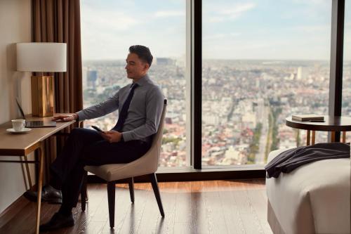 a man sitting at a desk in a room with a window at Sheraton Hai Phong in Hai Phong