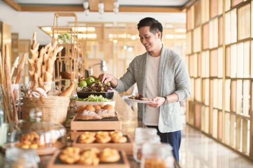 a man holding a plate of food in a bakery at Sheraton Hai Phong in Hai Phong