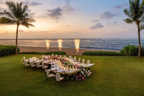 a long table on the beach with chairs and lights at The St. Regis Bali Resort in Nusa Dua
