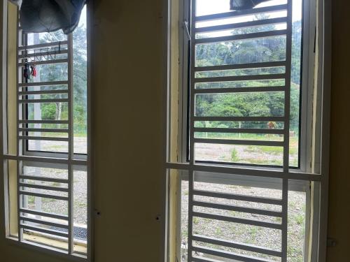 a window with shutters looking out at a yard at Jeli Heights Hill Homes in Jeli
