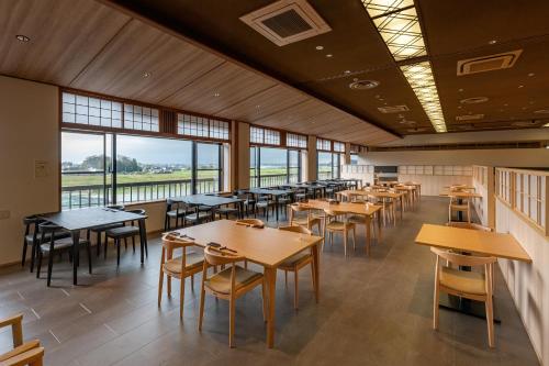 a dining room with tables and chairs and windows at 泰泉閣 in Asakura