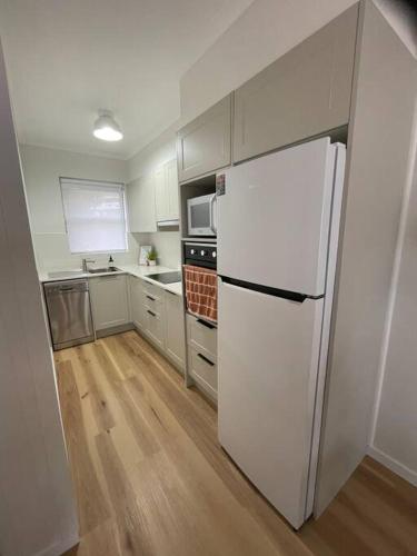 a kitchen with a white refrigerator and a stove at 'Rocks Retreat' - Dunbar Court Unit 2 - Renovated & Centrally Located in South West Rocks