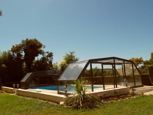 une maison en verre à côté d'une piscine dans l'établissement Gîte Belfloret, à Renneville