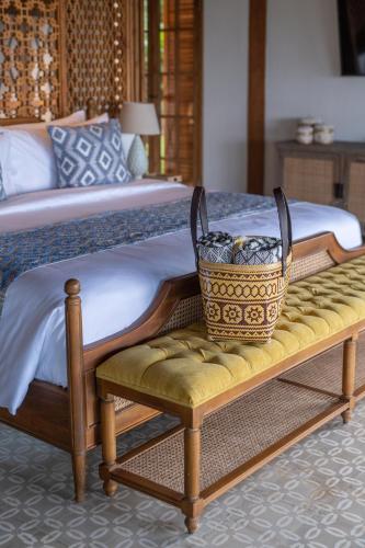 a bed with a bench with a basket on it at Umah Lusa in Munduk