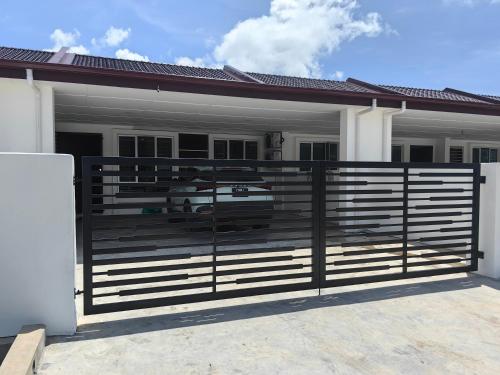 a fence in front of a house with a car at Win & Sha's Homestay in Miri