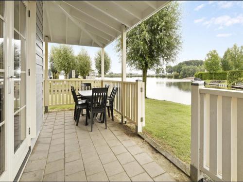 a porch with a table and chairs and a view of a lake at Bungalow in South Holland with Private Jetty in Simonshaven