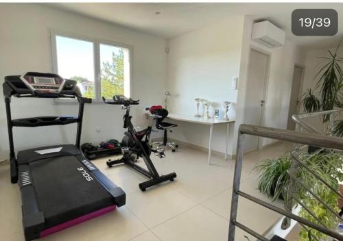 a room with a gym with a treadmill and a desk at LA BASTIDE DU SOLEIL avec piscine, calme, randonnée à proximité in Allegre Les Fumades