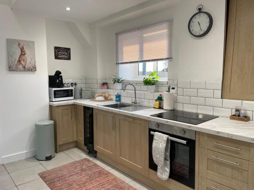 a kitchen with a sink and a clock on the wall at Rose barn hot tub holidays in the Cotswolds in Badsey